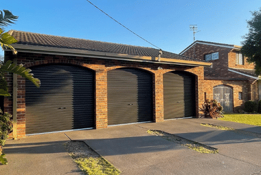 Triple roller garage doors black in brick garage