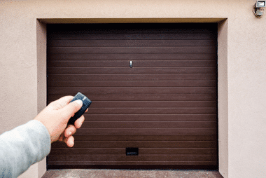 Brown custom sectional garage door with remote control held by hand